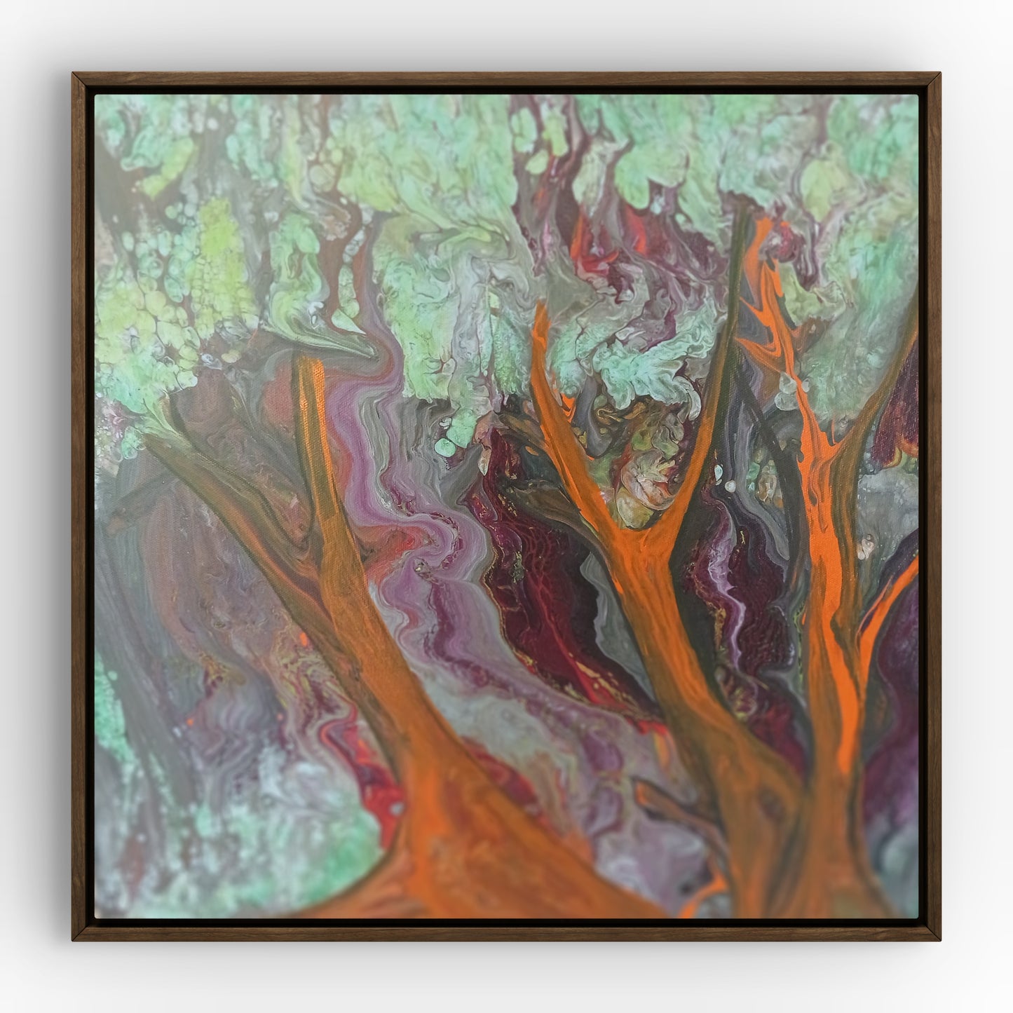 Abstract painted black frame wall art featuring swirling marbled paint in orange, purple, green, gray, and red, enclosed in a dark brown square frame against a light gray wall.